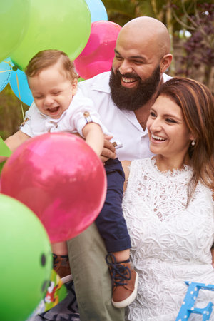 Smiling latino family of three in garden with small boy