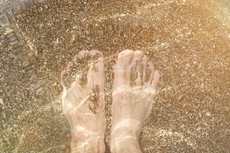 Man feet in sea water view from top in sun light