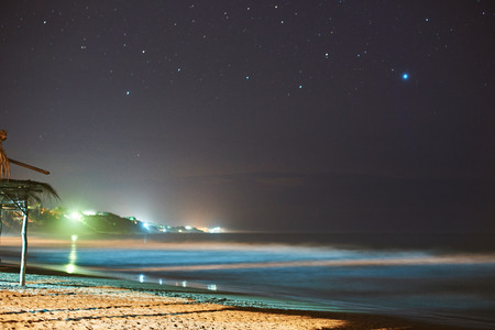 Sea coast at night with soft blurred water under stars skyの写真素材