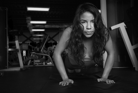 Hispanic girl doing push up in gym black and white coloursの写真素材