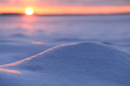 Christamas background with snowdrift. Morning sun illuminate snowdrift. Red rising sun on blured backdrop.の写真素材