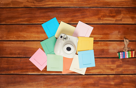 instant camera on top of colorful frames lay wooden table mockupの写真素材