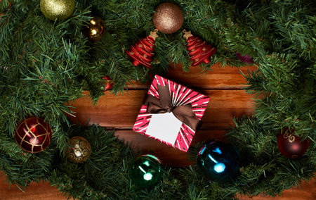 Christmas holiday background with pine and present box ribbon on wood background
