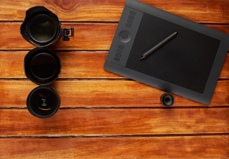 Photography dlsr lens on wood table with graphic designer tabletの写真素材
