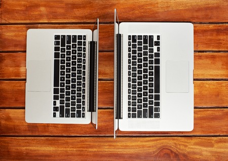 Two modern laptops on wooden table view from topの写真素材