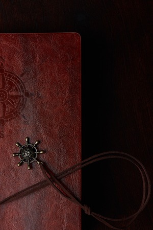 Closeup of half travel diary with brown leather cover on wooden tableの写真素材