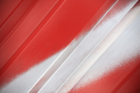 Close up of white painted line on red metal background. Red steel container wall with white line closeup. Red ribbed transportation container wall.の写真素材