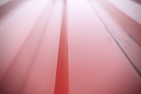 Red ribbed container wall close up. Red shiny background. Straight rows of steel closeup. Soft bokeh of ribbed metal.の写真素材