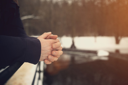 Close up mans hands outside on metal rail. Loneliness concept in warm tones. Mans hands on blurred natural background. Background in vintage colors.の写真素材