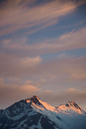 Mountain peak on sunset cloudy sky background. Orange dawn in alaska summitの写真素材