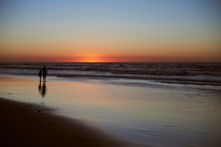 Father and kid stand on beach background. Sunset colorful dusk beach panorama with two peopleの写真素材