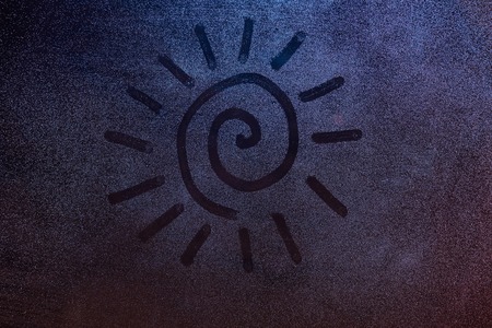Swirl shape sun draw on foggy window background. Concept drawing on frozen window night lightの写真素材