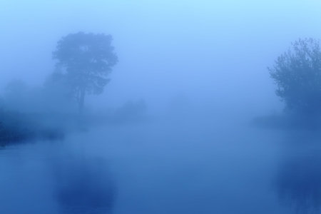 Fog over lake in the morning. Misty morning in blue colors. Beautiful morning landscape in blue...