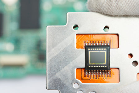 Small digital camera sensor in sciencer hand on electronic circuit background