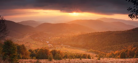 Gorgeous mountain evening landscape. Sun illuminate misty mountain scene. Beautiful autumn background. Nice halloween theme. Colorful trees on mountain valley at sunset.の写真素材