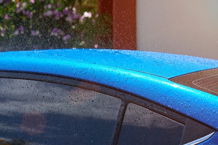 Wet blue car roof during rain in sunny day. Water drops on blue car roodの写真素材