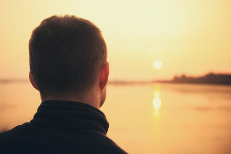 Man portrait from back on rising sun background. Man enjoy the silence in the morning. Good relaxation background. Free space on sunrise background.の写真素材