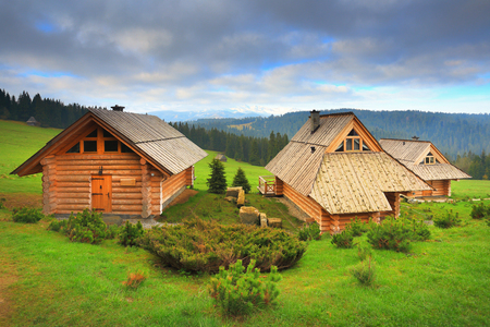 Ecological wooden houses on mounain hills. Wooden hotel on a sunny day. Beautiful place for rest. Morning landscape with green grass.の写真素材