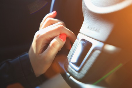 Fingers with pink manicure on steering wheel. Vivid pink nails close-up.の写真素材