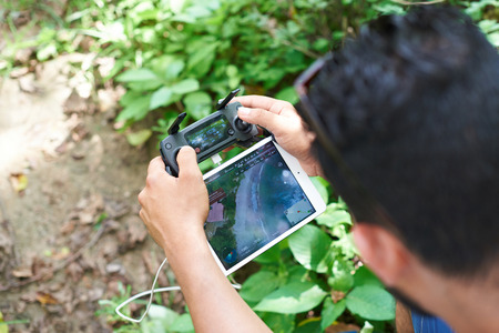 Los Angeles, USA - July 9, 2017:Man using DJI mavic drone controller with tablet. Man flying over beachのeditorial素材