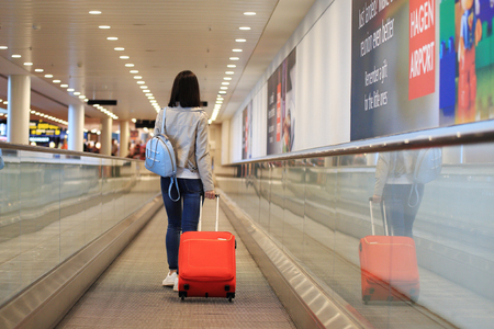 Copenhagen airport, Denmark - July 15, 2017: One girl with red suitcase on escalator in airport.のeditorial素材