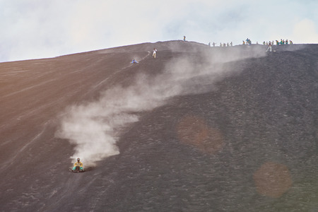 Volcano sand boarding activity in Nicaragua. Young woman on volcano board tour in Nicaraguaの写真素材