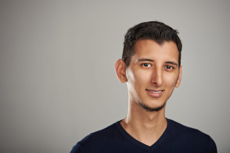 Portrait of smiling latino man isolated on gray background