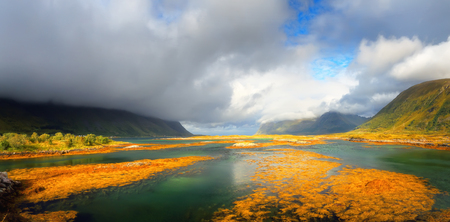 Mountain lake in day light. White clouds over transparent fjord water. Panoramic view at norwegian fjord.の写真素材