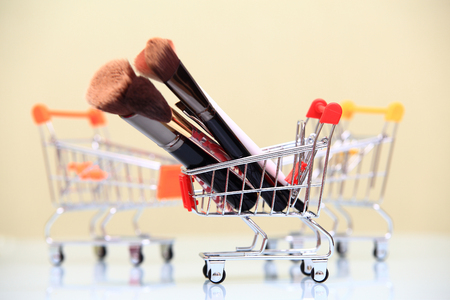 Make-up sale concept. Group of makeup brushes in toy shopping cart.の写真素材