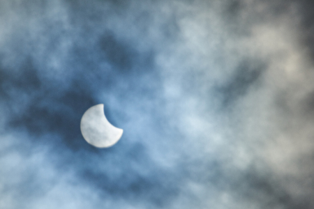oon over sun in eclipse on blue cloudy backgroundの写真素材