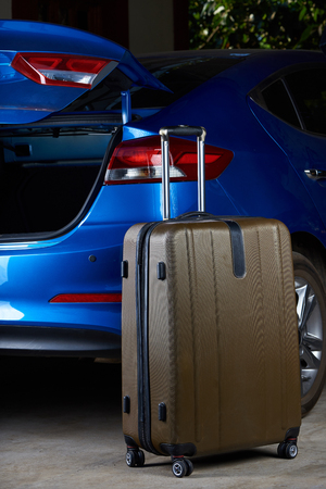One suitcase stand next to blue car open empty trunkの写真素材