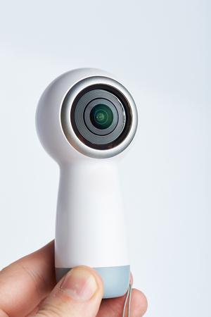Recording 360 video camera in hand close up view isolated on white backgroundの写真素材