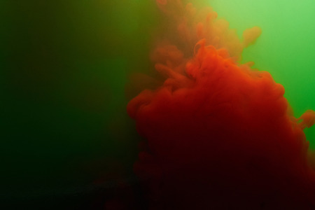 Splash of red ink in green water. Colorful liquid abstract backgroundの写真素材