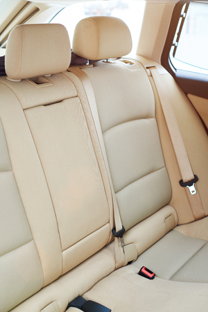 Clean brown back seat of modern car. Close-up of backseat car with seatbeltの写真素材