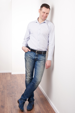 Positive smiling young man in casual outfit standing in officeの写真素材