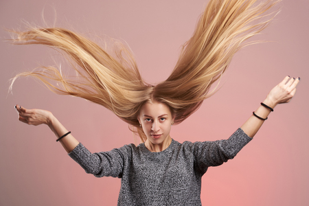 Portrait of young blonde woman with hair up isolated on pink backgroundの写真素材