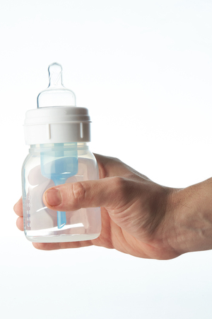 Empty plastic baby feeding bottle in hand isolated on white backgroundの写真素材
