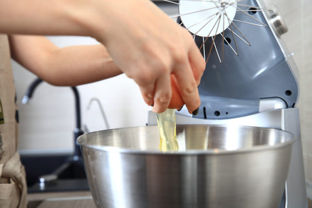 Process of cooking pie at home. Woman adds egg to dough.