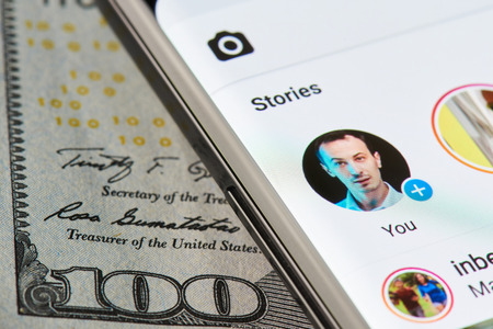 New york, USA - April 11, 2018: Instagram story on smartphone close-up on dollar currency backgroundのeditorial素材