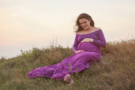 Young pregnant woman waiting for baby in natural backgroundの写真素材
