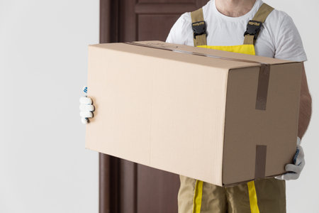 Delivery man with big box close-up. Professional moving goods background.
