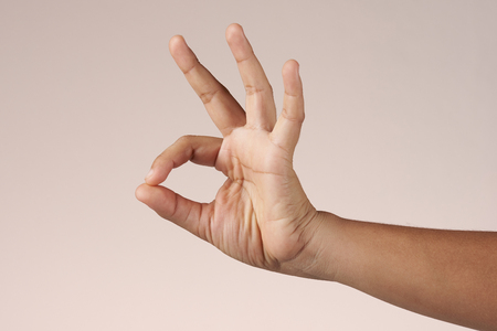 Hand show ok sign isolated on brown backgroundの写真素材