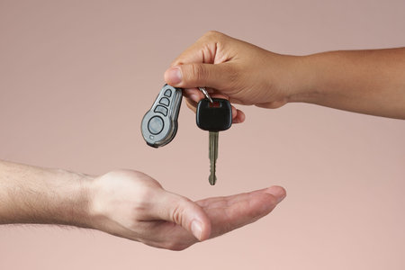 Giving car keys concept. Hand holding auto keys. Sell vehicle service. Hands hanging keys isolated