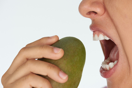 Hungry woman on diet theme. Biting green mangoの写真素材