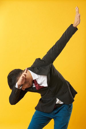 Young asian man showing dab posture isolated on yellow backgroundの写真素材