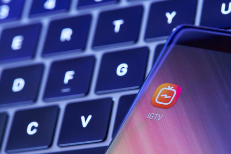 New york, USA - July 6, 2018: Instagram IGTV icon on smartphone screen lay on laptop keyboardのeditorial素材
