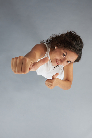 Woman with thumbs up isolated on grey background above top viewの写真素材