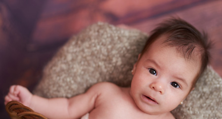 Portrait of cute baby girl laying in basket above top viewの写真素材