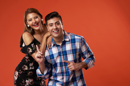 Laughing young latin couple in orange color studio backgroundの写真素材