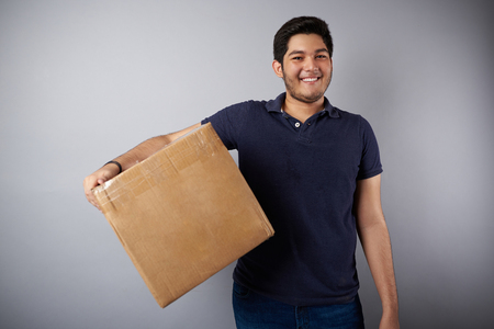 Delievery young man with box isolated on gray backgroundの写真素材